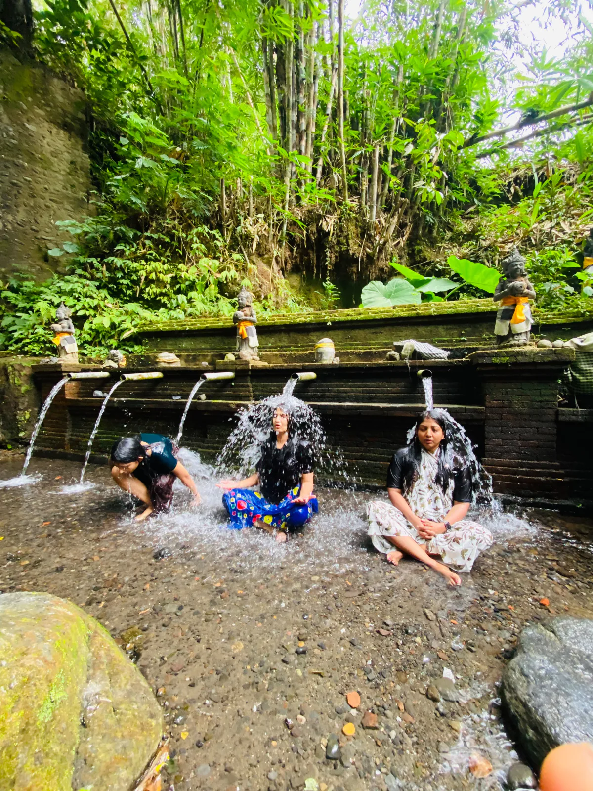 Guests seated under the water spouts during a Balinese purification ceremony